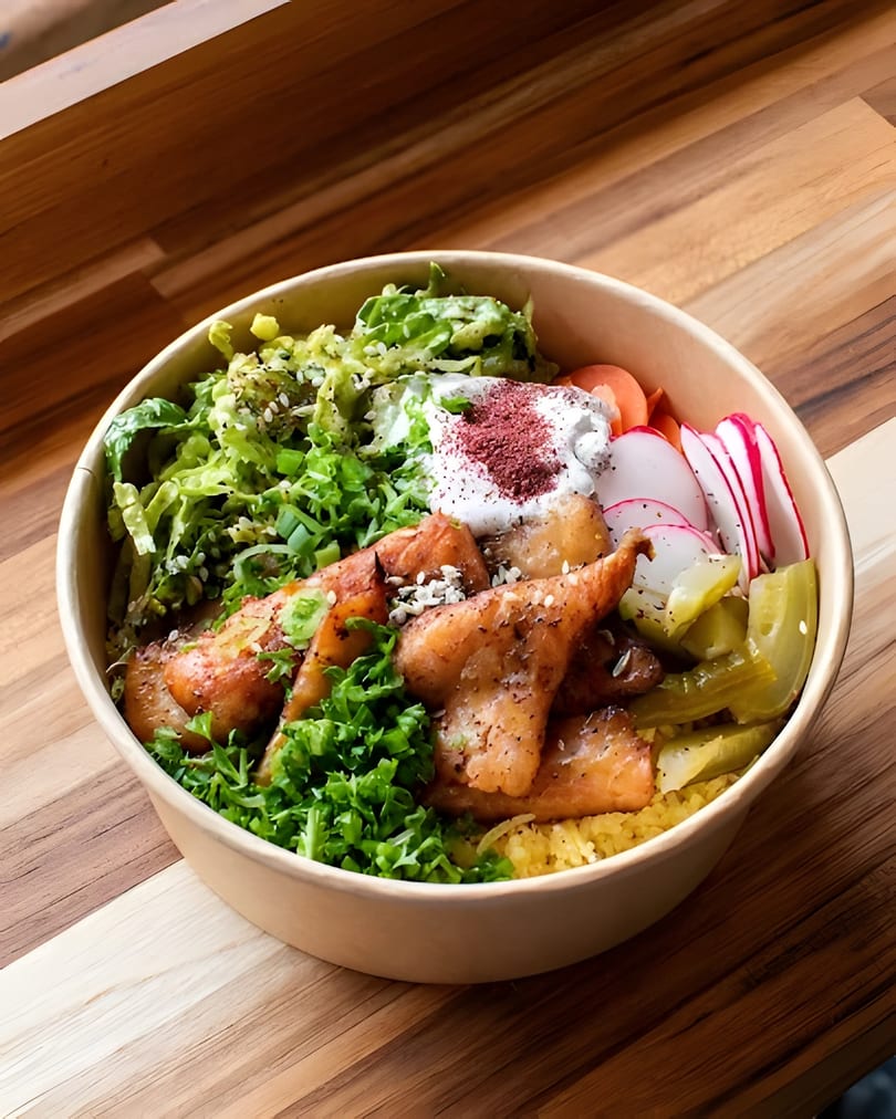 A vibrant salmon rice bowl with fresh greens, radishes, pickles, and a dollop of sauce.